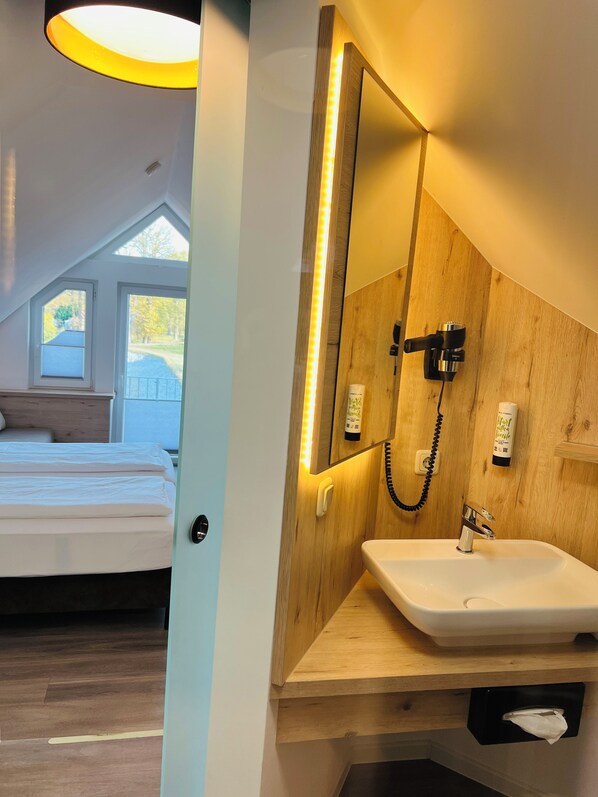 Une salle de bain moderne avec un meuble-lavabo en bois, un grand miroir et un luminaire au plafond.