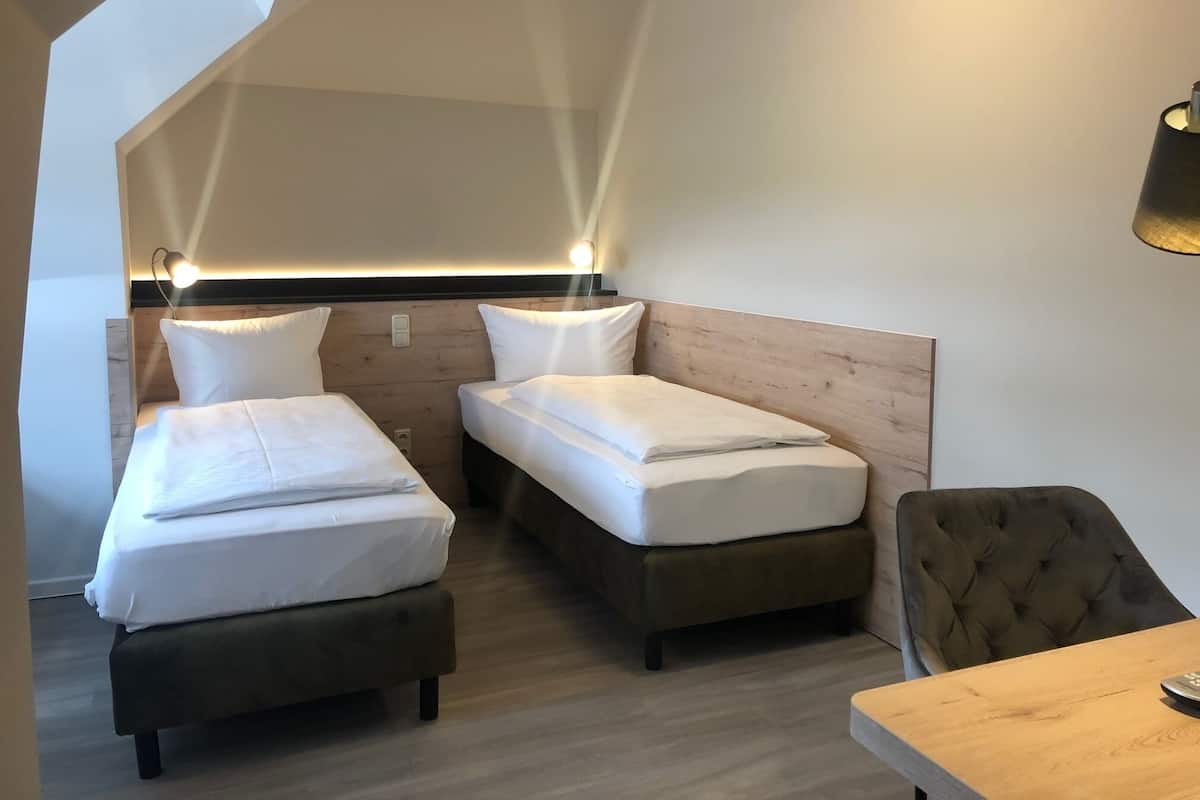 A room with two beds, a chair, and a table.