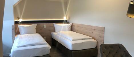 Une chambre avec deux lits, une chaise et une table.