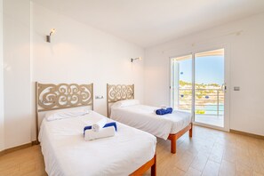 A hotel room with two beds, a balcony with a view of the beach, and a sliding glass door. - Villa Voramar with sea views. Cala D'Or (Cala d´Or)