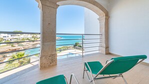 Un balcon donnant sur la mer, une chaise et un pilier en pierre.