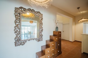A staircase with a mirror, a wooden cabinet, and a hanging light fixture in a room with tiled flooring and a door in the background. - Holiday house Nino close to the sea with sea view (Pula)