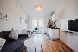 A modern living room with a sofa, a small round table, a kitchen area with a TV, and a dining area with a table and chairs. - Holiday house Nino close to the sea with sea view (Pula)