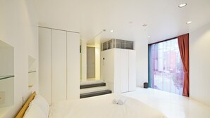 A modern hotel room with a large bed, a separate seating area, a staircase leading to a balcony, and a large window with curtains. - 【Free pickup for over 4 nights stay】Center of the Tokyo Luxury 4-storey Villa (Minato City)