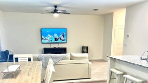 Ein modernes Wohnzimmer mit einer Couch, einem Esstisch und einer Küchenzeile mit Bar.
