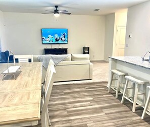 Ein modernes Wohnzimmer mit einer Couch, einem Esstisch und einer Küchenzeile mit Bar.