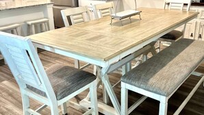 Ein Essbereich mit einem Holztisch, weißen Stühlen und Bänken.