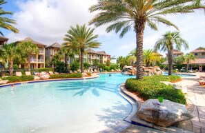 Ein Poolbereich eines Resorts mit Palmen, Liegestühlen und einem klaren, blauen Pool.