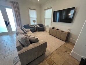A living room with a sectional sofa, a TV mounted on the wall, and a small side table. - Spacious Pet Friendly 4-bedroom gated community in Destin, Fl with a golf cart (Destin)