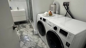 A laundry room with a front-loading washer and dryer, a small sink, and a window. - Cozy Modern 3BR With Free Parking Fast Wifi (Richmond Hill)