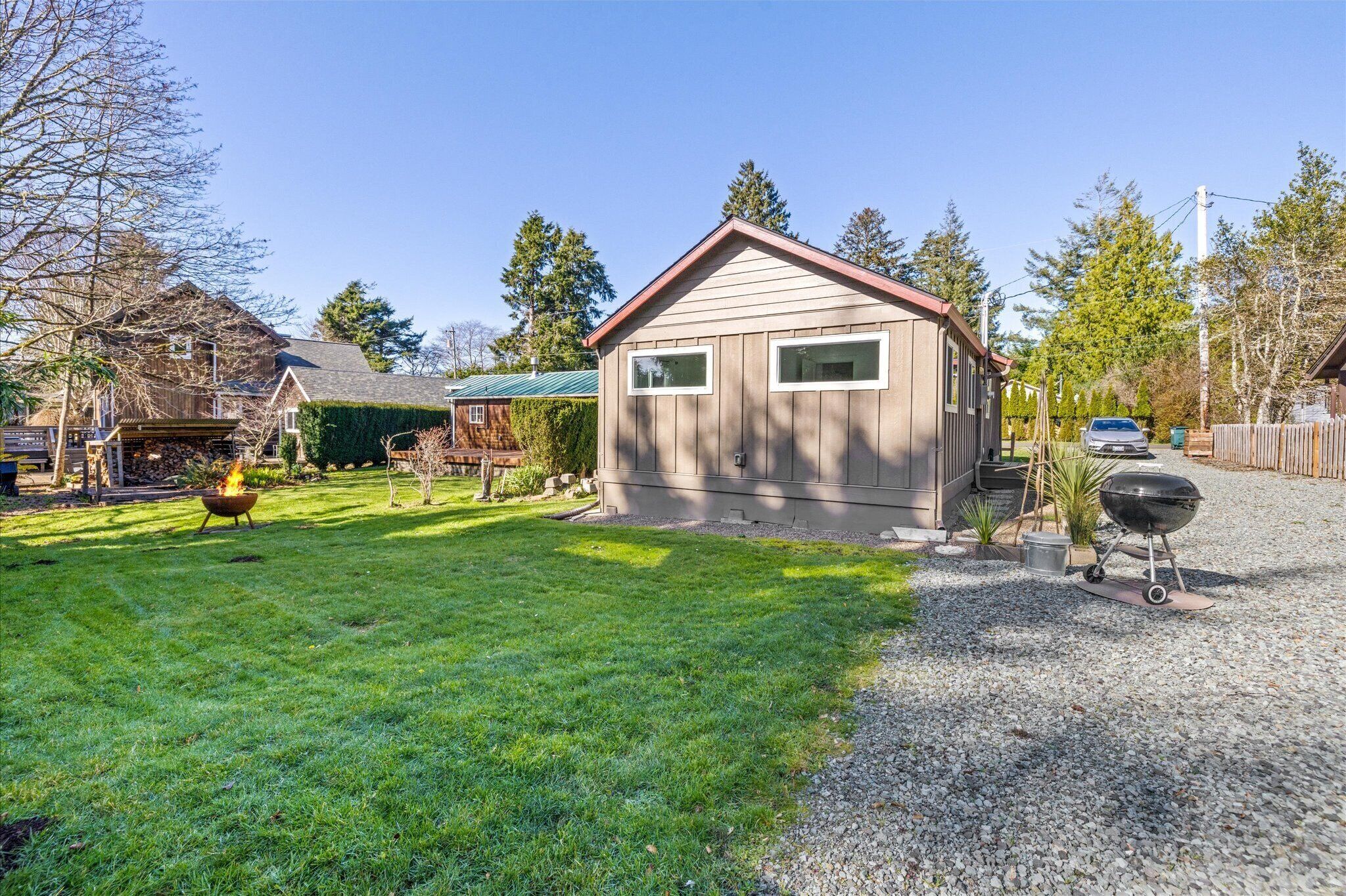 Charming rental property featuring spacious lawn, mature trees, and peaceful residential setting with convenient gravel parking area.