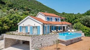 A two-story house with a swimming pool, stone walls, and a hillside backdrop. - Luxury Villa Blue Dream (Đenovići)