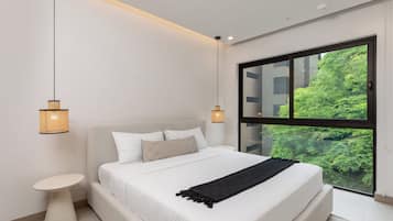 Un dormitorio moderno con una cama grande, dos lámparas de noche, una mesita auxiliar pequeña y un ventanal con vistas a zonas verdes.