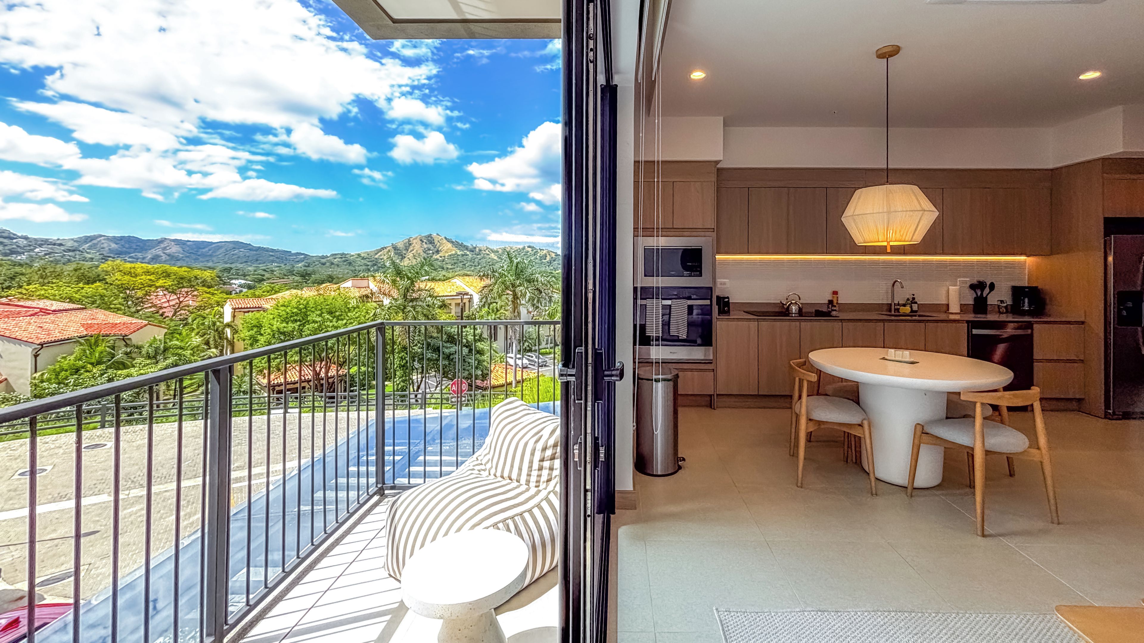 En balkon med udsigt til bjerge og et moderne køkken med spiseplads.