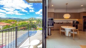 En balkon med udsigt til bjerge og et moderne køkken med spiseplads.