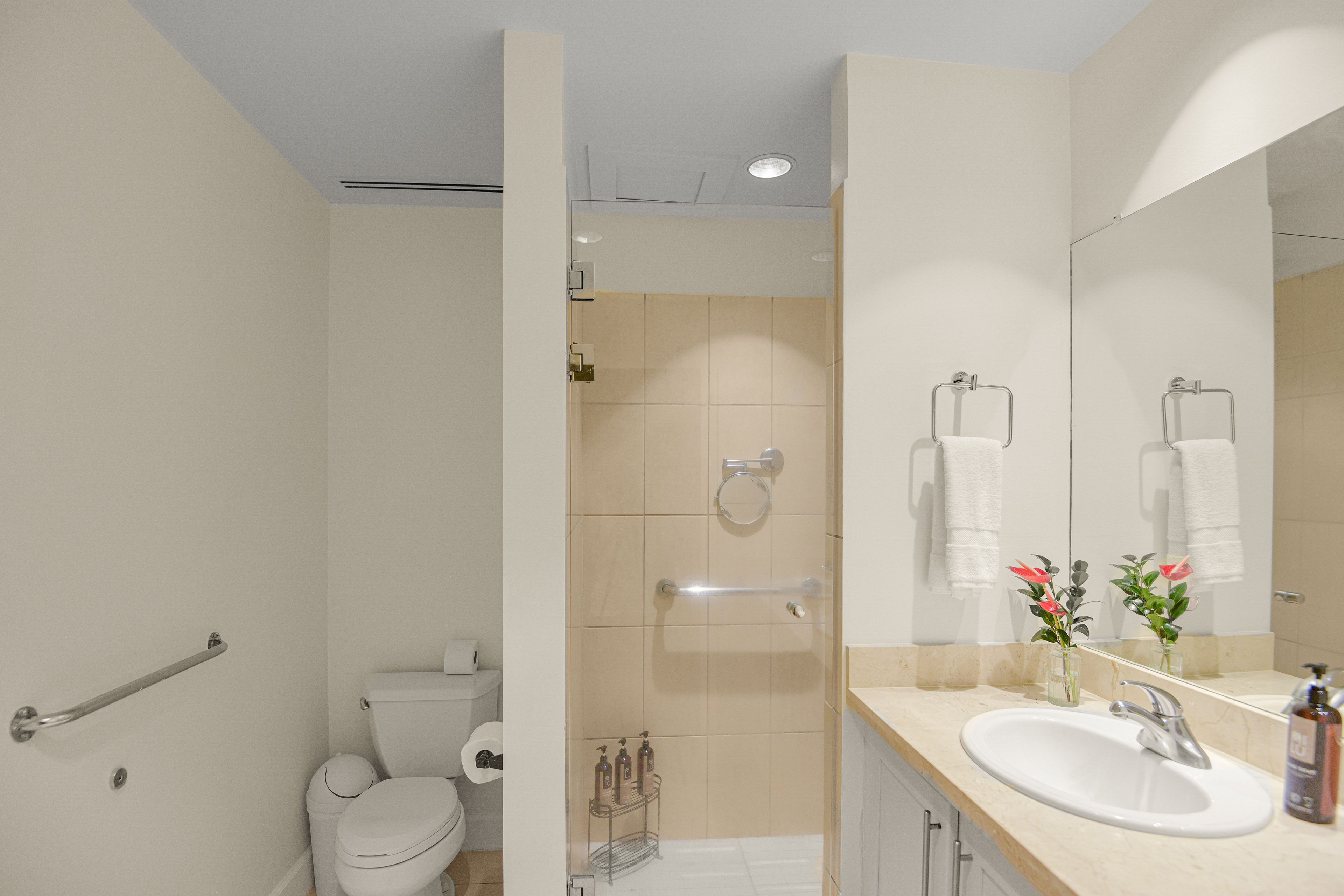 Un baño moderno con inodoro, ducha, lavabo y espejo.