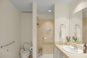 Un baño moderno con inodoro, ducha, lavabo y espejo.