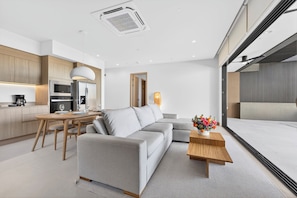 A modern living space with a sofa, dining table, and kitchen area.