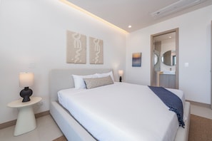 A modern hotel room with a large bed, bedside tables, a mirror, and wall art.