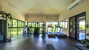 Ein geräumiges Fitnessstudio mit unterschiedlichen Trainingsgeräten, großen Fenstern und Blick auf Grünflächen.