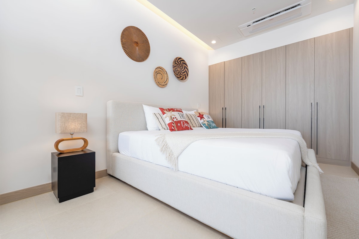 A modern bedroom with a large bed, a nightstand, a wall-mounted lamp, and a wardrobe.