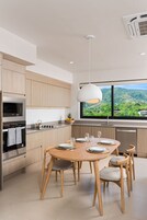 Una cocina moderna con armarios de madera, un horno de acero inoxidable y un comedor con mesa y sillas de madera.
