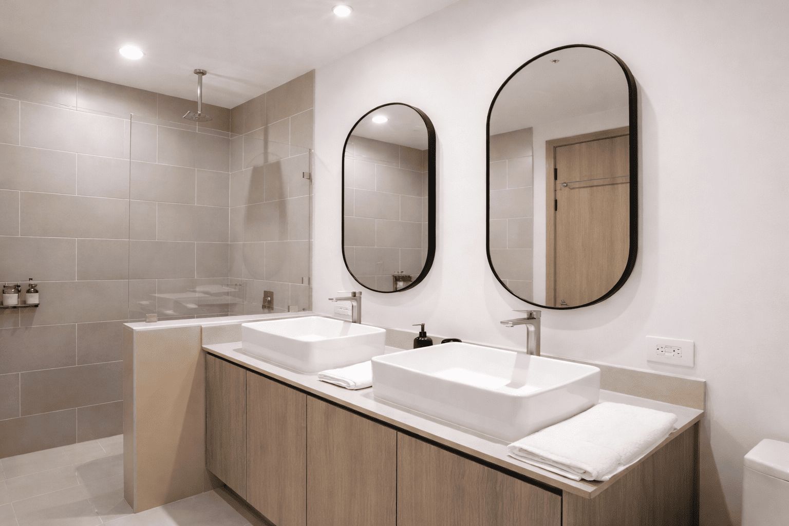 A modern bathroom with two sinks, a shower, and two mirrors.