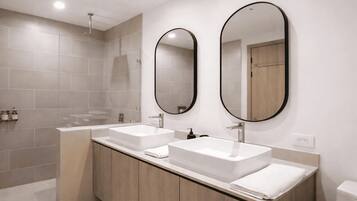 A modern bathroom with two sinks, a shower, and two mirrors.
