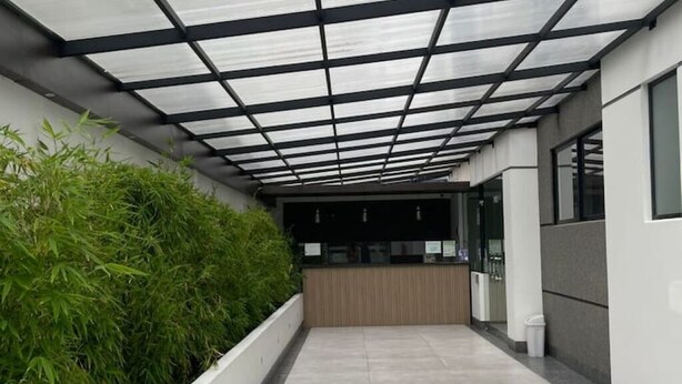 A corridor with a glass ceiling, a reception desk, and a planter with green foliage.