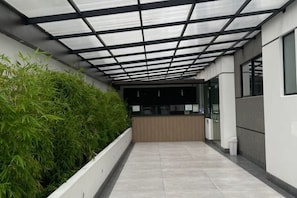 A corridor with a glass ceiling, a reception desk, and a planter with green foliage. - Two bedroom apartment in La Paz (La Paz)