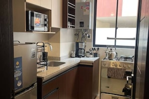 A compact kitchen with a refrigerator, microwave, sink, and stove. - Two bedroom apartment in La Paz (La Paz)