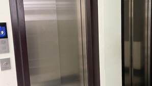 An elevator interior with metallic walls and a control panel on the left.