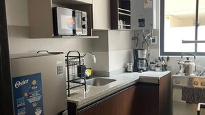 A kitchen with a refrigerator, sink, and stove.