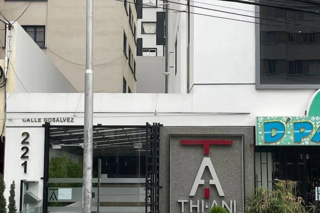 A building with a sign reading "Calle Gosalvez 221" and a prominent "T" sign with "THIANI" below it.