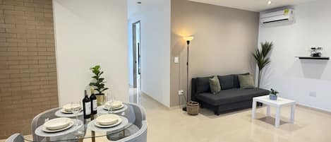 Una sala de estar moderna con comedor, un sofá, una mesita de centro y un equipo de aire acondicionado.