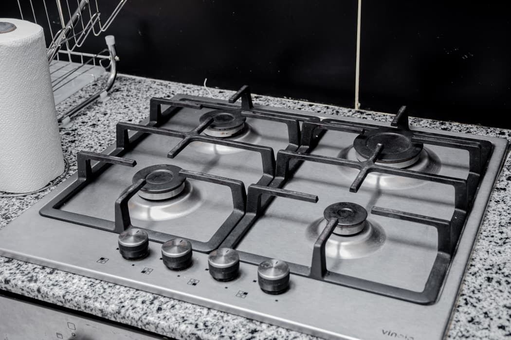 A kitchen with a gas stove, a roll of paper towels, and a metal rack.