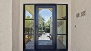 Une porte-fenêtre moderne à glissière donne accès à un espace extérieur couvert, équipé d’une piscine et d’un escalier.