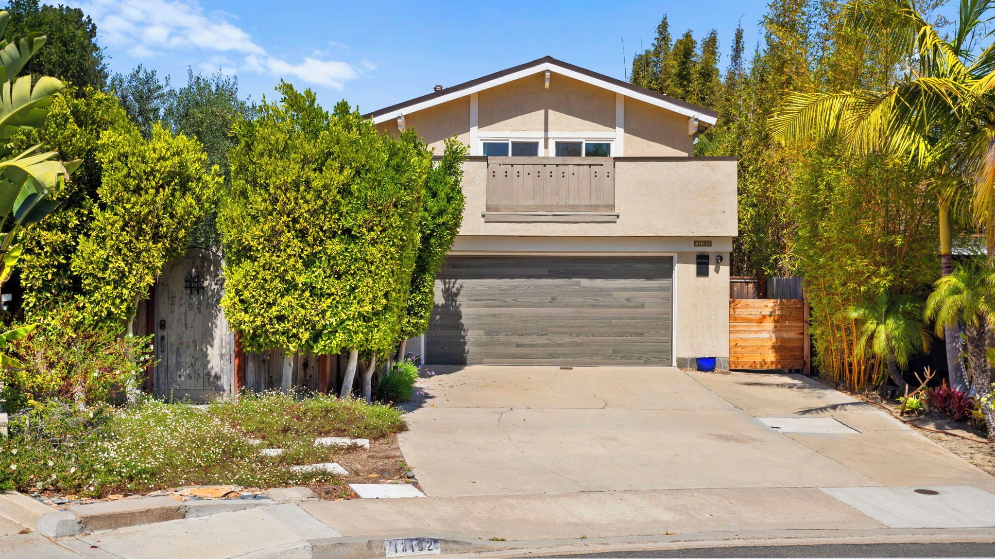 A modern two-story house with a garage, surrounded by lush greenery and a well-maintained garden.