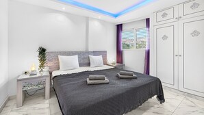 Ein modernes Schlafzimmer mit Bett, Nachttischen, einer Pflanze und einem Kleiderschrank.