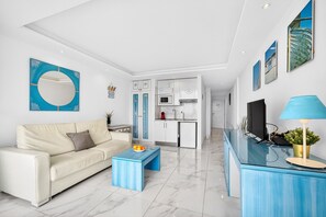 A modern living room with a sofa, coffee table, and a kitchen area in the background. - My Sun My Ocean - Sea View Apartment (Playa de Las Americas)