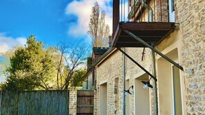 A stone building with a balcony, a wooden fence, and a clear blue sky. - Favorite house 1h15 Paris jacuzzi Fontainebleau countryside Moret Sur Loing (Lorrez-le-Bocage-Préaux)