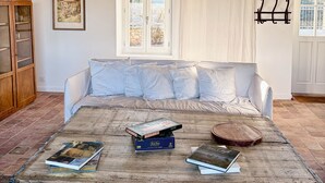 A cozy room with a wooden table, a white sofa, and a window with curtains. - Favorite house 1h15 Paris jacuzzi Fontainebleau countryside Moret Sur Loing (Lorrez-le-Bocage-Préaux)