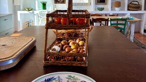 A dining area with a wooden table, a decorative plate, and a wicker basket filled with fruits and vegetables. - Favorite house 1h15 Paris jacuzzi Fontainebleau countryside Moret Sur Loing (Lorrez-le-Bocage-Préaux)