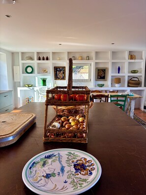 A dining area with a wooden table, a decorative plate, and a wicker basket filled with fruits and vegetables. - Favorite house 1h15 Paris jacuzzi Fontainebleau countryside Moret Sur Loing (Lorrez-le-Bocage-Préaux)