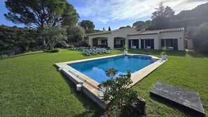 Ein Schwimmbecken, eine überdachte Terrasse und ein Haus mit einem Ziegeldach.