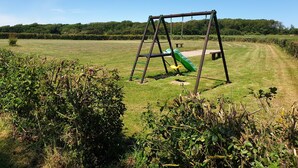 A swing set in a grassy field with a clear sky. - Gîte rural Le Vent du Nord – Ferme des 4 Vents (Audinghen)