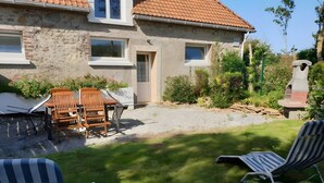 A house with a stone exterior, a tiled roof, a patio with outdoor furniture, and a grassy yard. - Gîte rural Le Vent du Nord – Ferme des 4 Vents (Audinghen)
