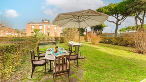 Eine Terrasse mit Tisch für vier Personen, umgeben von St ühlen und einem Sonnenschirm, der Schatten spendet.