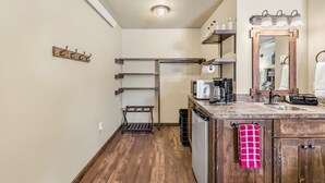 A compact kitchen with wooden cabinets, a built-in microwave, and a sink. - Old West Studio Cabin Near Yellowstone (Island Park)