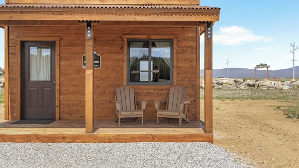 A wooden building with a sign reading 'BLACKSMITH,' two Adirondack chairs, a window, and a door. - Old West Studio Cabin Near Yellowstone (Island Park)